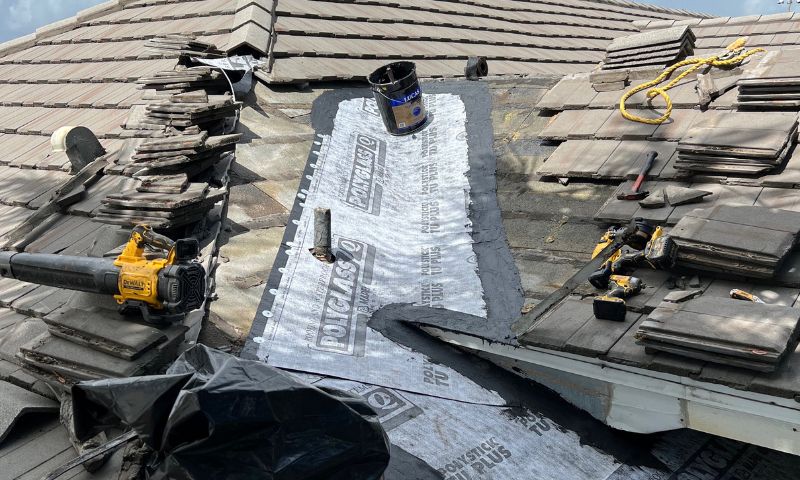 roofers fixing damaged roof tiles